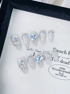 Vue macro de faux ongles stiletto longs avec paillettes œil de chat et strass en cœur