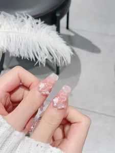 Macro shot of 3D white flowers, pearls, and laser bow on pink coffin press-on nails