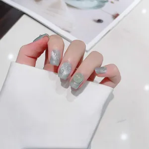 Cat eye press-on nails in grey-green with pearls and golden bow accessories
