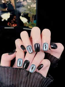 Detail of blue cat-eye and black handmade press-on nails with shimmering glitter finish