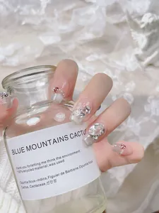 Macro detail of handmade blush press-on nails with white butterflies and 3D pearls