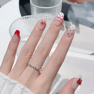 Unghie finte fatte a mano con fiocchi rossi e pois bianchi su sfondo di vetro elegante