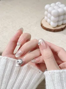 Detail of handmade cat-eye press-on nails with pearls and heart-shaped rhinestones