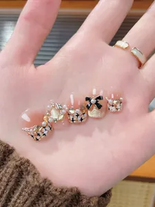 Detailed view of handmade press-on nails with pearls, black bows, and star motifs