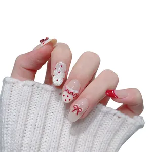 Unghie finte fatte a mano con fiocchi rossi e glitter su sfondo in maglia bianca morbida