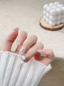 Macro detail of nude gradient press-on nails with cat-eye shine and rhinestone accents