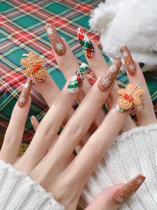 Détail de faux ongles de Noël avec bonhomme de pain d'épice 3D et motifs flocons blancs