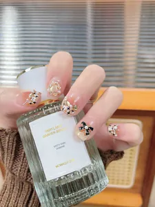 Elegant cat-eye press-on nails with pearls, black bows, and sparkles on nude base
