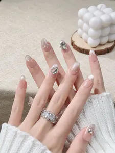 Detail of handmade press-on nails with nude pink gradient, pearls, and rhinestones