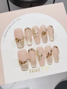 Detail of handmade press-on nails with golden butterfly 3D charms and glitter