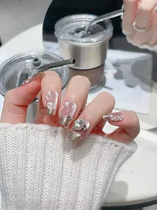 Detail of luxury press-on nails with champagne gold tips, leaf art and rhinestone