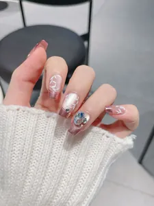 Macro detail of French press-on nails with white leaf art and large faceted rhinestone