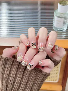 Macro detail of cat-eye press-on nails with black bows, pearls, and golden glitter accents