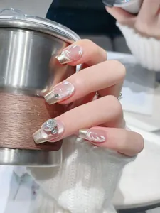 Macro shot of French press-on nails with champagne gold edges and rhinestone details
