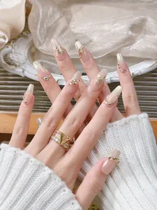 Detail of handmade press-on nails with golden butterflies and a V-shaped crystal ring