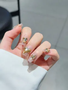 Detail of handmade press-on nails featuring sparkling gold hearts and rhinestones