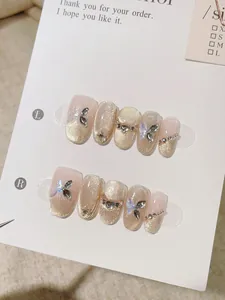 Gros plan d'ongles faits main avec papillons 3D et effet œil de chat doré chic