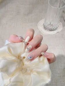 Détail de faux ongles de luxe avec papillons 3D dorés, strass et effet œil de chat