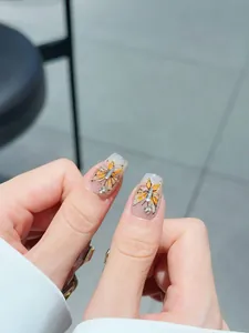 Macro view of handmade press-on nails featuring orange butterfly wings and silver glitters