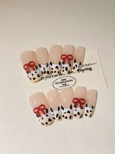 Detail of press-on nails with leopard patterns and 3D red bows on a textured background