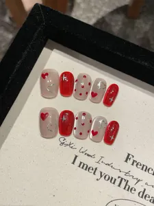 Macro detail of red cat-eye and nude heart pattern press-on nails set with silver stars