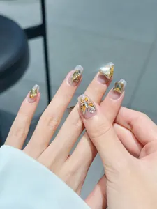 Detail of luxury press-on nails with 3D amber butterflies and oversized heart crystals