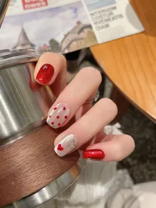 Detail of red glitter and silver cat-eye press-on nails with heart and dot patterns