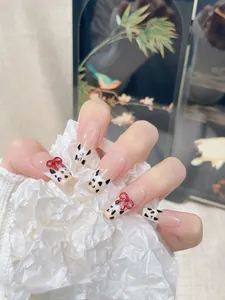 Detail of handmade French press-on nails with cow print tips and 3D red bows