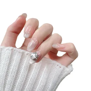 Handmade almond press-on nails with nude pink cat-eye gradient and crystal rhinestones