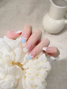 Detail view of oval press-on nails featuring hand-painted floral art and 3D lace trim