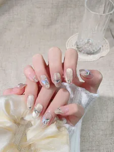 Détail de faux ongles de luxe avec papillon 3D argenté et zircons sur base nude oeil de chat