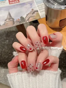 Macro detail of red glitter nails with silver cross stars and red heart polka dot patterns
