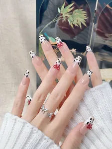 Detailed view of long coffin press-on nails with cow print tips and red 3D bows