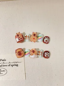 Detail of 3D Capybara handmade press-on nails for kids with brown plaid and rainbow patterns