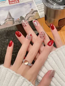Detailed view of red cat-eye press-on nails with heart patterns and glitter finish