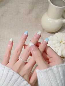 Detail of floral press-on nails with blue French tips and pearl relief on neutral fabric