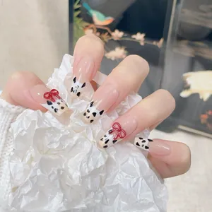 Handmade long ballerina press-on nails with cow print design and 3D red bows