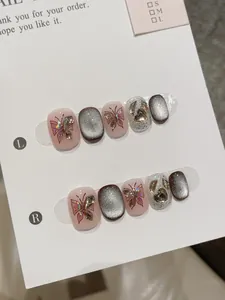 Macro shot of press-on nails featuring cat-eye finish and 3D metal butterfly charms