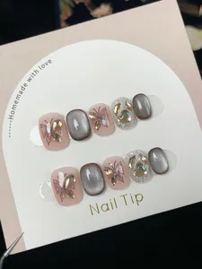 Detail of handmade cat eye nail tips with glitter butterfly designs and rhinestones