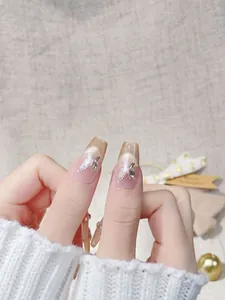 Detail view of long coffin press-on nails with 3D butterflies, pearls, and cat eye glitter