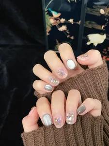 Detail showing silver cat eye press-on nails with 3D butterfly charms and sequins