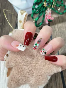 Detalle de uñas postizas de Navidad hechas a mano con diseños de muñeco de nieve y pino