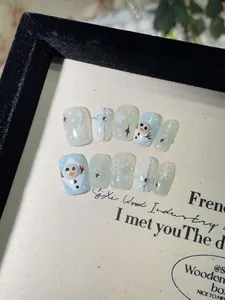 Detailopname van handgemaakte kerstnagels met sneeuwpop, strikjes en blauwe sneeuwvlokken