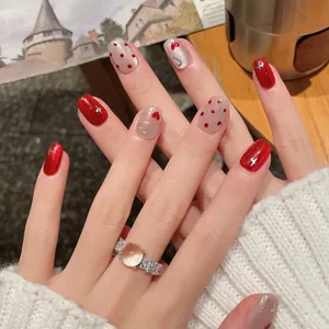 Short red cat-eye press-on nails with silver stars, heart patterns, and red polka dots