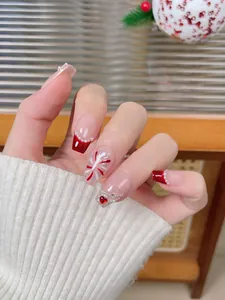 Close-up of red French nails with pearl accents, heart gems, and snowflake details