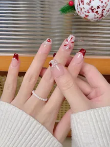 Detail of red festive press-on nails with 3D heart gems and pearl snowflake art