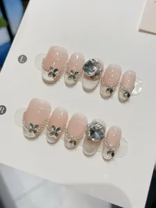 Close-up of handmade nude cat eye press-on nails with big heart rhinestones and pearls