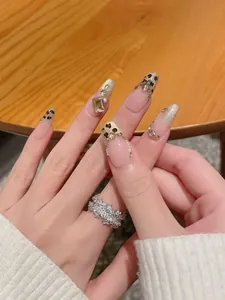 Close-up of leopard print press-on nails with amber diamonds and champagne glitter