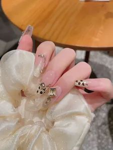 Detail of handmade press-on nails with leopard print, golden rhinestones and cat-eye finish