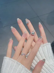 Detail of French press-on nails with silver glitter, pearls and rhinestones on oval tips